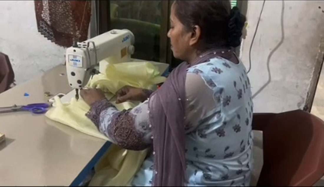 A seamstress working with yellow fabric at a sewing machine